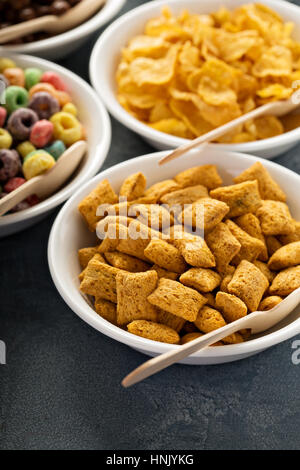 Varietà di cereali freddi in bianco ciotole con cucchiai di legno, veloce colazione per bambini Foto Stock