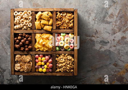 Varietà di cereali freddi in una scatola di legno, veloce colazione per bambini overhead shot Foto Stock