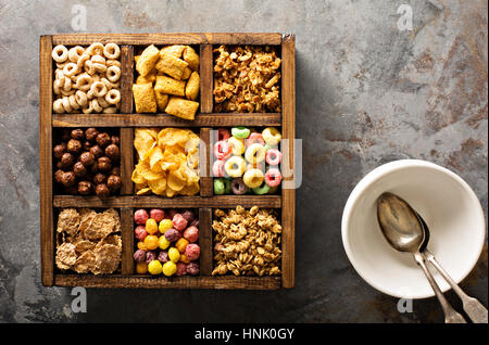 Varietà di cereali freddi in una scatola di legno, veloce colazione per bambini overhead shot Foto Stock