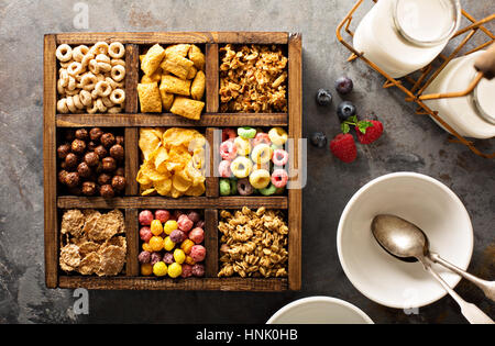 Varietà di cereali freddi in una scatola di legno, veloce colazione per bambini overhead shot Foto Stock