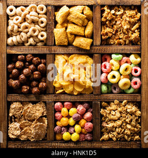 Varietà di cereali freddi in una scatola di legno, veloce colazione per bambini overhead shot Foto Stock