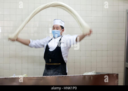 Lo chef prepara spaghetti tirati a mano. Ristorante Noodle, Ürumqi, regione autonoma dello Xinjiang, Cina. Foto Stock