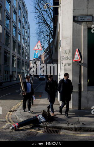 I giovani uomini a piedi passato un danneggiato bollard, investiti da un veicolo il 13 febbraio 2017, nella città di Londra, Regno Unito. Foto Stock