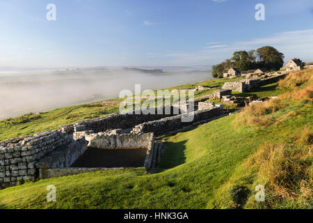 Il Vallo di Adriano: Housesteads Roman Fort - un serbatoio di acqua, angolo torre e le latrine comunali, con oltre, la vista verso sud-ovest Foto Stock