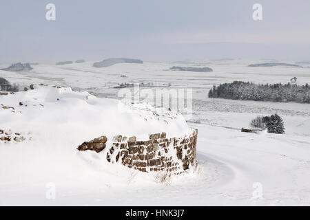 Il Vallo di Adriano: l'angolo sud-ovest di Housesteads Roman Fort curtain wall, visto qui nella neve profonda da fuori il Fort Foto Stock