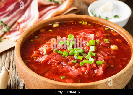 Tradizionali ucraine zuppa di barbabietole borscht nella ciotola di legno con aglio panini pampushka e Dry cured pancetta di maiale su tavola in legno rustico Foto Stock