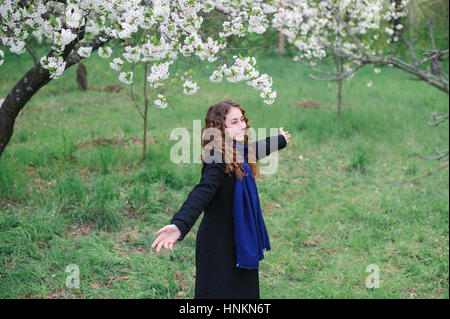 Bella felice giovane donna camminare in un fiorente giardino di primavera Foto Stock