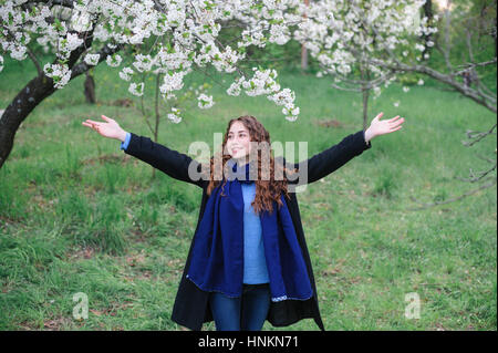 Bella felice giovane donna camminare in un fiorente giardino di primavera Foto Stock