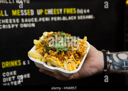 Cheesy fries con croccante di cipolle e coriandolo da asporto. Foto Stock