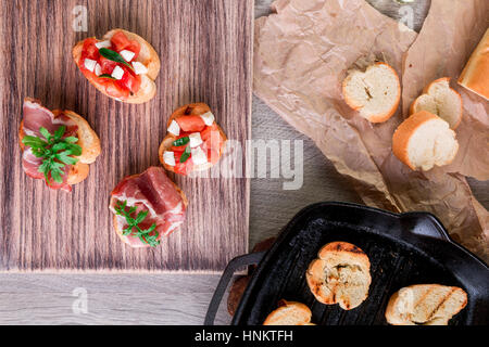 La bruschetta ingredienti per la preparazione con la scheda e il coltello. Il cibo italiano. Foto Stock