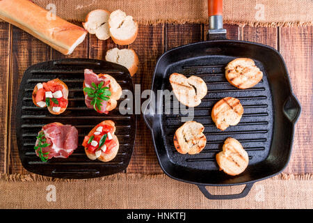 La bruschetta ingredienti per la preparazione con la scheda e il coltello. Il cibo italiano. Foto Stock