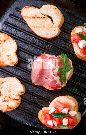 La bruschetta ingredienti per la preparazione con la scheda e il coltello. Il cibo italiano. Foto Stock