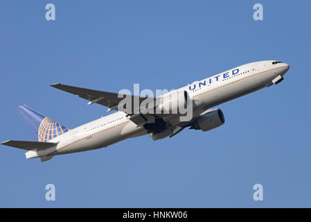 United Airlines Boeing 777-224ER N76010 il decollo dall'Aeroporto di Londra Heathrow in cielo blu Foto Stock