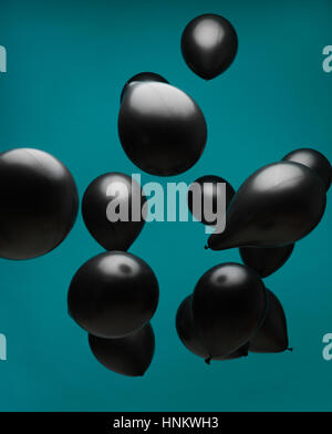 Nero ballons floting di fronte a uno sfondo blu Foto Stock