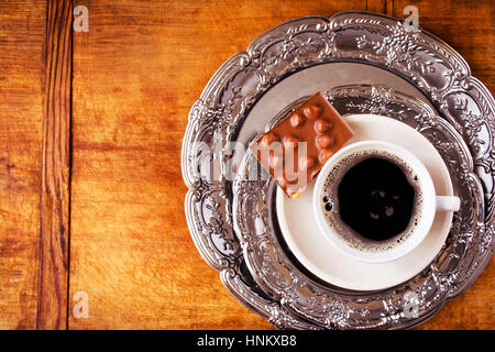 Caffè caldo e barra di cioccolato servito su piastre di vintage su sfondo di legno, vista dall'alto Foto Stock