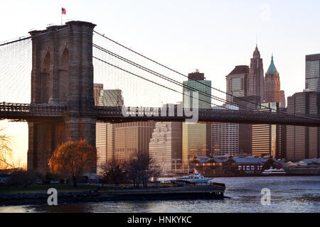 Ponte di Brooklyn girato dal litorale di Brooklyn. prese in prima serata al tramonto. Gli edifici sullo skyline e il ponte sono illuminati. Foto Stock
