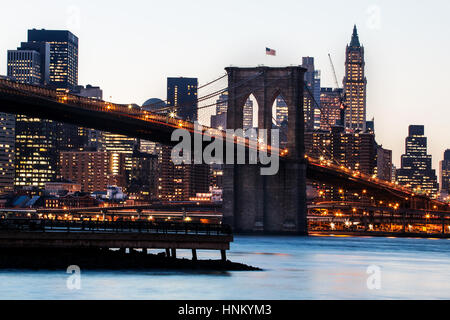 Ponte di Brooklyn girato dal litorale di Brooklyn. prese in prima serata al tramonto. Gli edifici sullo skyline e il ponte sono illuminati. Foto Stock