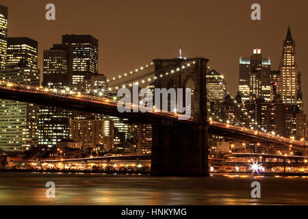 Ponte di Brooklyn girato dal litorale di Brooklyn. prese in prima serata al tramonto. Gli edifici sullo skyline e il ponte sono illuminati. Foto Stock