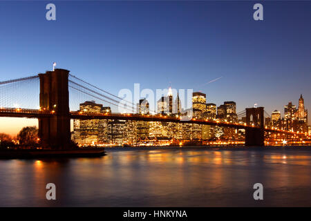 Ponte di Brooklyn girato dal litorale di Brooklyn. prese in prima serata al tramonto. Gli edifici sullo skyline e il ponte sono illuminati. Foto Stock