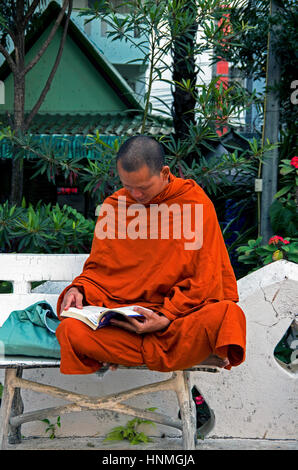 Monaco buddista seduta su una panchina con lettura a Wat Phra Sing a Chiang Mai, Thailandia. Foto Stock