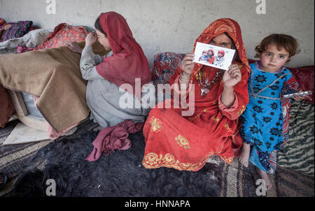 Afghanistan, Wakhan corridoio,una famiglia a casa vecchia donna che mostra una foto di famiglia,due bambini vicino a lei, vestito in tradizionali abiti etnici. Foto Stock