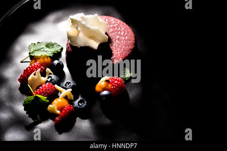 Crema di vino con mousse di frutta fresca sulla piastra scuro dessert spazio per il layout del testo Foto Stock