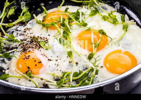 Sostenuto uova sunny side up con i piselli freschi la germogliazione Foto Stock