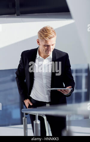 Un uomo in un vestito con la compressa in mano l'ufficio Foto Stock