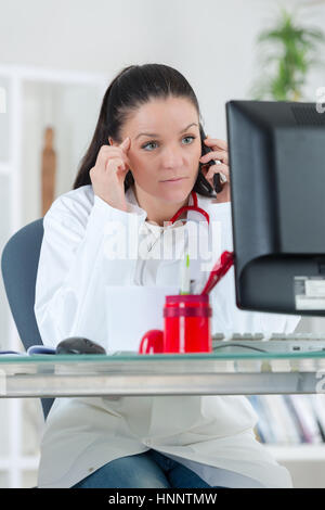 Ritratto di giovane donna medico sul telefono in ufficio Foto Stock