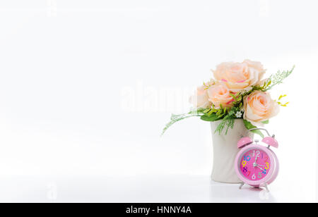 Rosa sveglia e mazzo di fiori su fondo bianco con copia spazio, messa a fuoco selettiva sull'orologio leggera profondità di campo Foto Stock