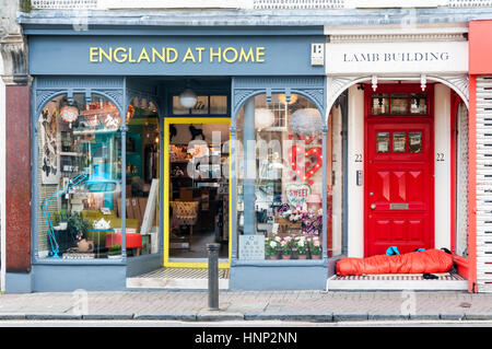 L'ironia di un senzatetto traversina ruvida in Brighton, dormendo in una porta avanti in Inghilterra alla Home shop Foto Stock