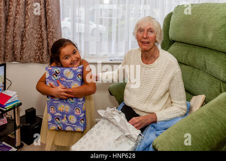 Una razza mista di bambino e sua nonna apertura presenta il giorno di Natale, Sussex, Regno Unito Foto Stock