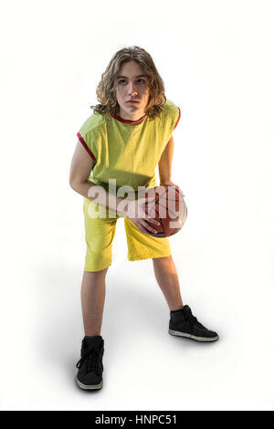 Ragazzo con lunghi capelli biondi che indossa una maglia verde in una posizione accovacciata in possesso di un basket Foto Stock