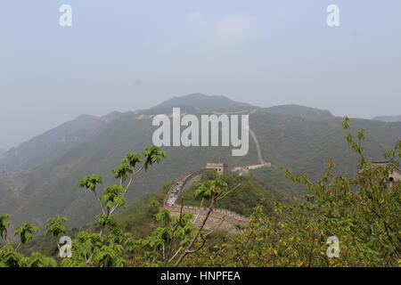 La Grande Muraglia della Cina al Mutyanu. Mountanious paesaggio con lo smog da Pechino in background Foto Stock