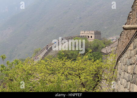 La Grande Muraglia della Cina al Mutyanu. Mountanious paesaggio con lo smog da Pechino in background Foto Stock