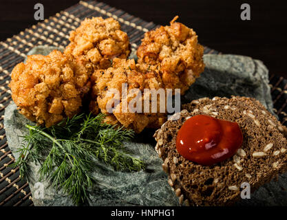 In casa costolette di carne in pastella con prezzemolo, ketchup e pane su pietra Foto Stock