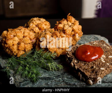 In casa costolette di carne in pastella con prezzemolo, ketchup e pane su pietra Foto Stock