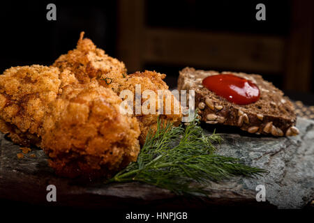 In casa costolette di carne in pastella con prezzemolo, ketchup e pane su pietra Foto Stock