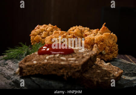 In casa costolette di carne in pastella con prezzemolo, ketchup e pane su pietra Foto Stock