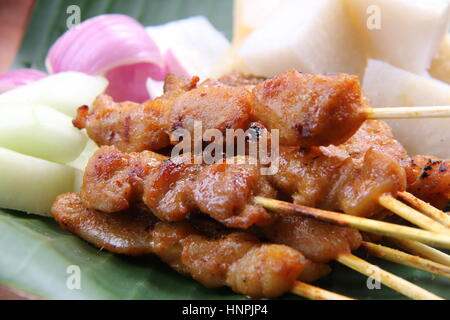 Pollo satay. Popolare il cibo alla griglia di Singapore e Malaysia, serviti con salsa di arachidi, torta di riso, cetrioli, e lo scalogno. Foto Stock