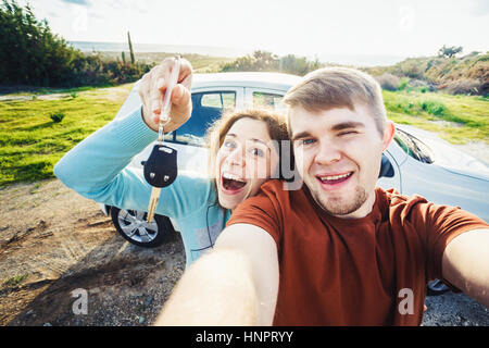 Giovane coppia divertenti con i tasti per nuova auto all'aperto Foto Stock