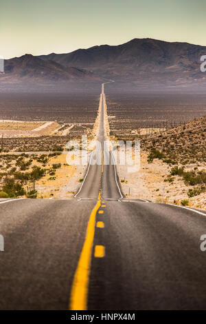 Classic vista verticale di un interminabile dritta strada che corre attraverso il paesaggio arido della famosa Valle della Morte in una giornata di sole in estate, CALIFORNIA, STATI UNITI D'AMERICA Foto Stock