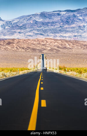 Classic vista verticale di un interminabile dritta strada che corre attraverso il paesaggio arido della famosa Valle della Morte con estremo calore haze in una giornata di sole, STATI UNITI D'AMERICA Foto Stock