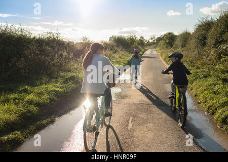 Una famiglia in bicicletta con la madre e i due figli in campagna. Foto Stock