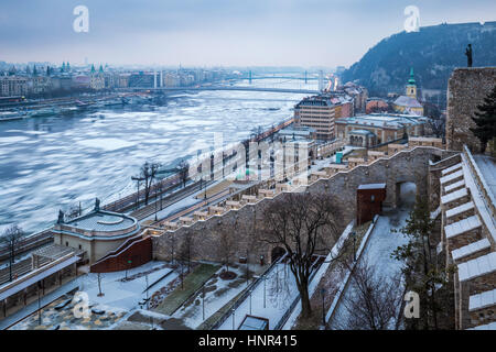 Budapest, Ungheria - panoramica vista sullo skyline del Varkert Bazar e gelido Fiume Danubio preso dal Castello di Buda (Palazzo Reale) su un nuvoloso mattino invernale Foto Stock