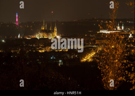 Il Petrin Lookout Tower in Praga illuminata con il tricolore con il castello di Praga nella parte anteriore. Bella notte paesaggio urbano Foto Stock