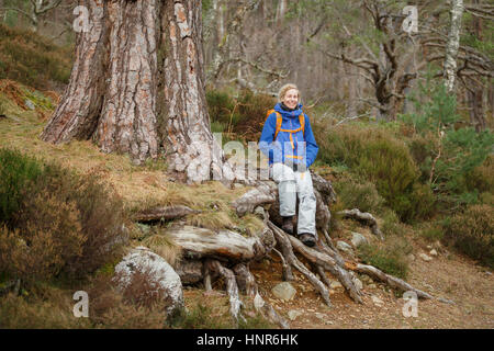 Donna assume un riposo durante una escursione di foresta in Scozia Foto Stock