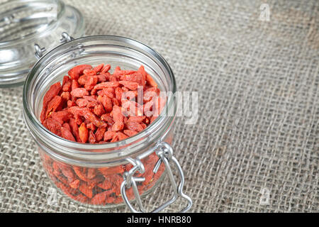 Essiccati goji bacche in un vaso su lino sfondo, spazio per il testo. Foto Stock