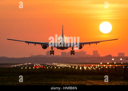 Aereo passeggeri è lo sbarco durante una splendida alba. Il velivolo è quasi atterrato sulla pista. Foto Stock