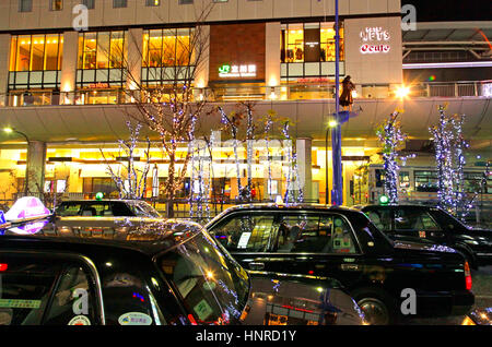 Notte di Natale Scape fila di taxi in attesa di clienti di fronte Tachikawa Stazione ferroviaria Tokyo Giappone Foto Stock